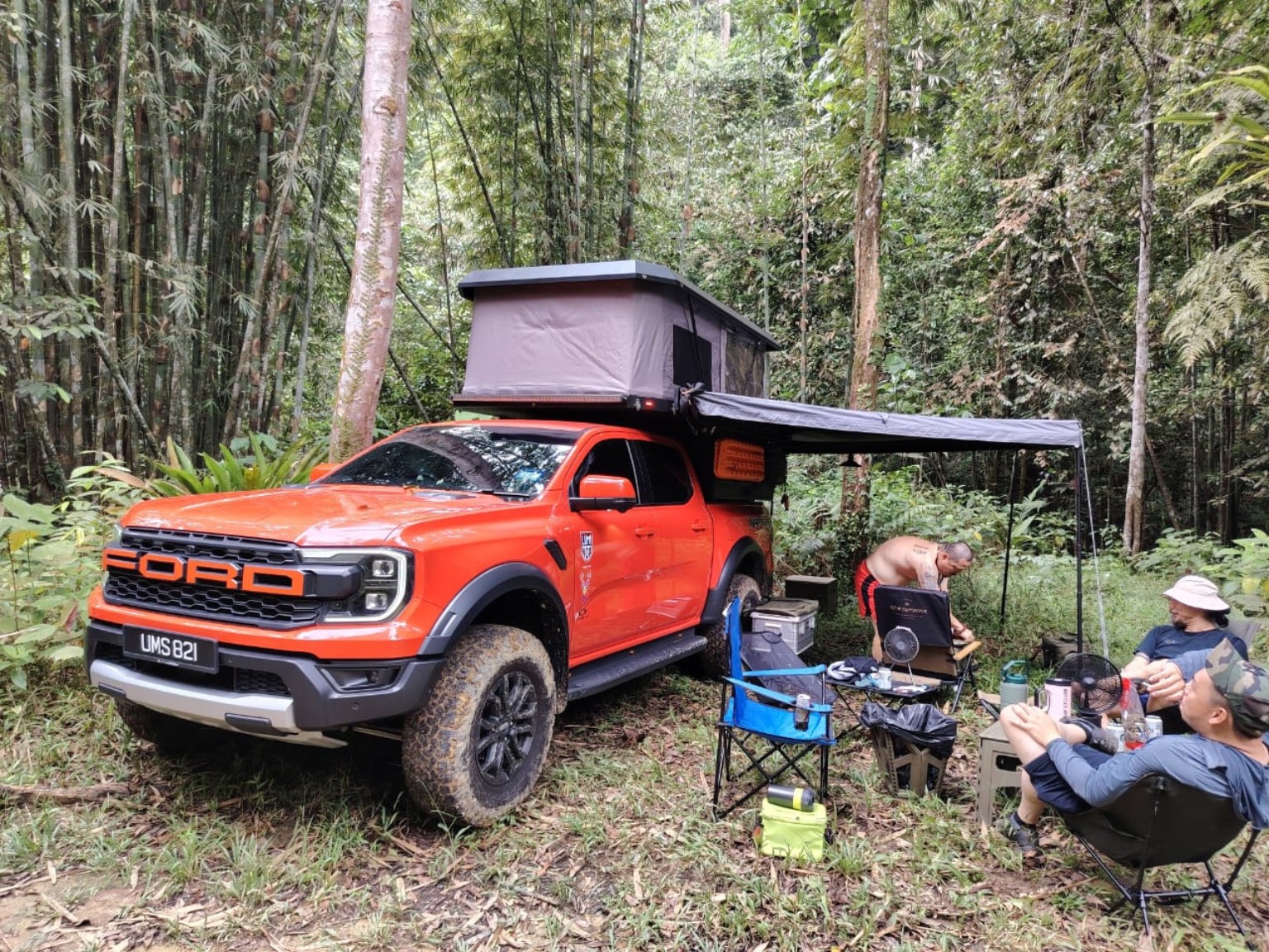 Friends relaxing at a truck camper retreat in the jungle
